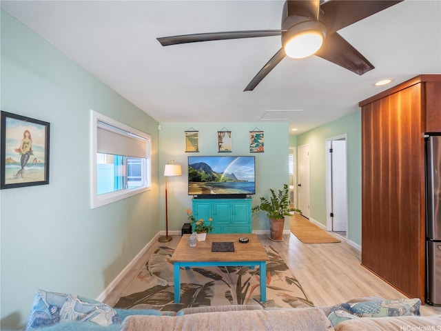 living area featuring light wood-style floors, a ceiling fan, and baseboards
