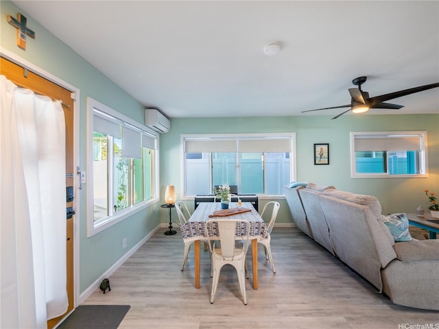 dining space featuring a wall unit AC, light wood finished floors, a ceiling fan, and baseboards