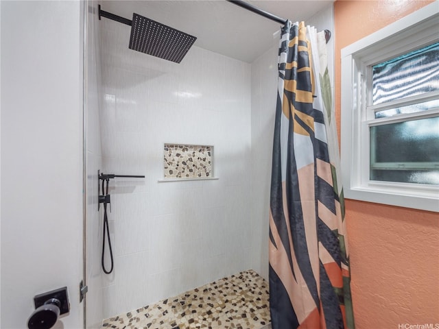 full bathroom featuring a textured wall and tiled shower