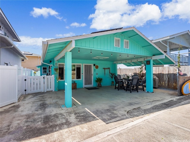 rear view of property with a gate, a fenced backyard, a carport, and a patio area