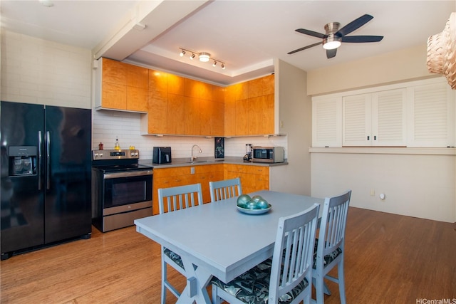 kitchen featuring backsplash, a ceiling fan, appliances with stainless steel finishes, a sink, and light wood-style flooring