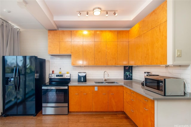 kitchen with backsplash, appliances with stainless steel finishes, wood finished floors, a sink, and light countertops