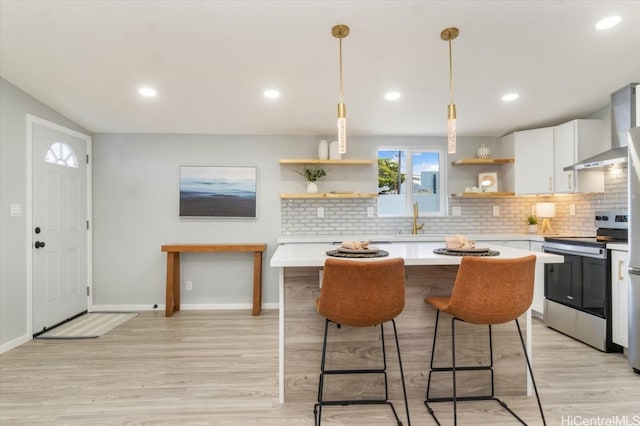 kitchen with stainless steel range with electric stovetop, a sink, open shelves, wall chimney exhaust hood, and light countertops