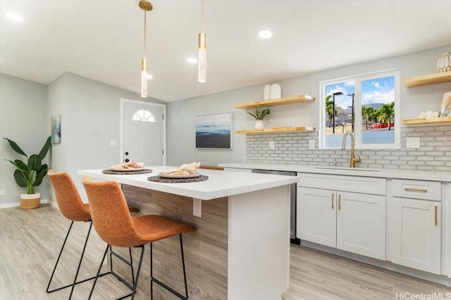 kitchen with decorative backsplash, open shelves, a sink, a center island, and light wood-type flooring