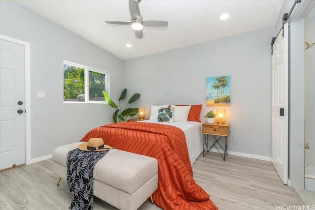 bedroom featuring baseboards, a barn door, light wood finished floors, and recessed lighting
