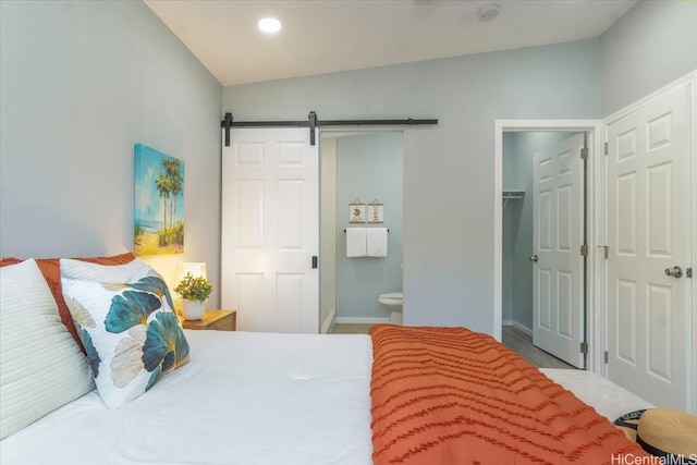 bedroom with recessed lighting, ensuite bath, a barn door, baseboards, and a spacious closet