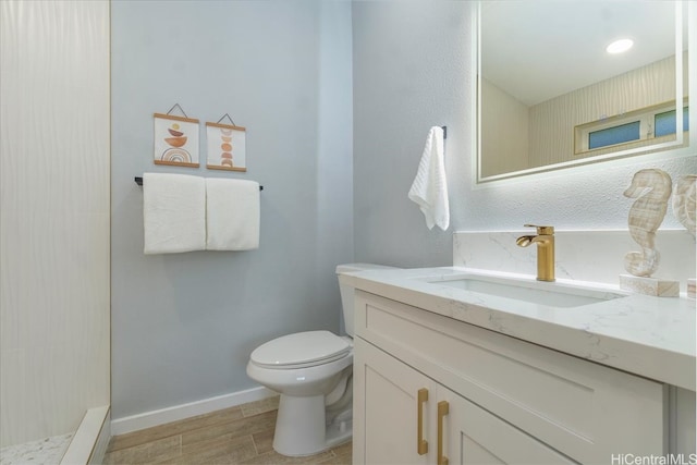 bathroom featuring wood finished floors, vanity, toilet, and baseboards