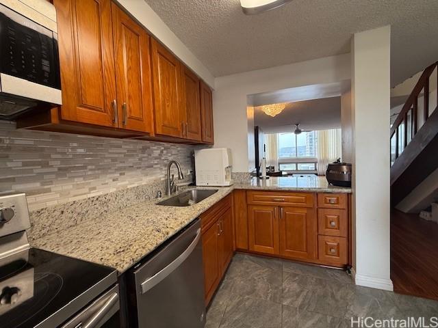 500 University Ave Unit 917, Honolulu, HI 96826 - kitchen featuring brown cabinetry, decorative backsplash, light stone countertops, a sink, and stainless steel appliances