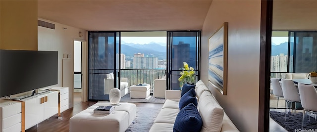 living area with dark wood-type flooring, a mountain view, visible vents, and a wall of windows