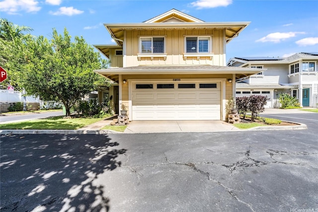 view of front of house featuring aphalt driveway, an attached garage, stone siding, and board and batten siding