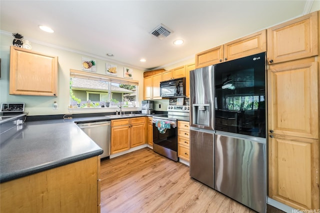 kitchen with a sink, visible vents, light brown cabinets, dark countertops, and appliances with stainless steel finishes
