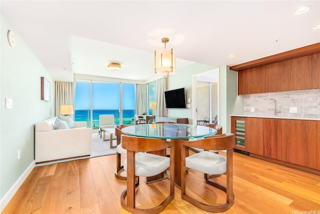 2139 Kuhio Ave Fl 34Th, Honolulu, HI 96815 - dining area with light wood-type flooring, baseboards, wine cooler, and a wall of windows