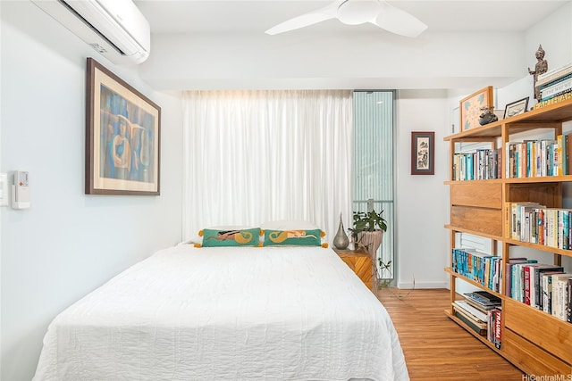 bedroom featuring wood finished floors, ceiling fan, and an AC wall unit