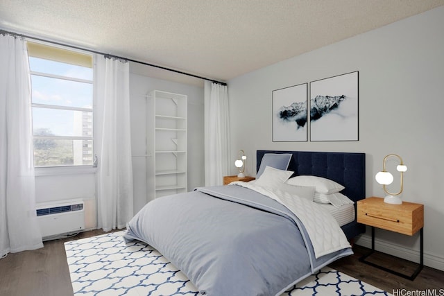 3161 Ala Ilima St Unit 811, Honolulu, HI 96818 - bedroom with a textured ceiling, wood finished floors, an AC wall unit, and baseboards