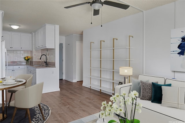 3161 Ala Ilima St Unit 811, Honolulu, HI 96818 - kitchen featuring a sink, white cabinets, light wood-type flooring, a ceiling fan, and a textured ceiling