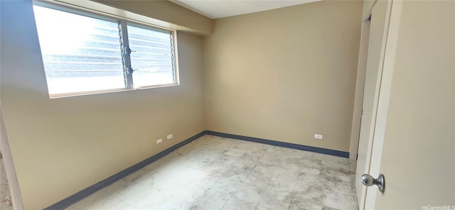 unfurnished room featuring marble finish floor and baseboards