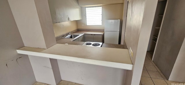 kitchen featuring light tile patterned flooring, a sink, and freestanding refrigerator