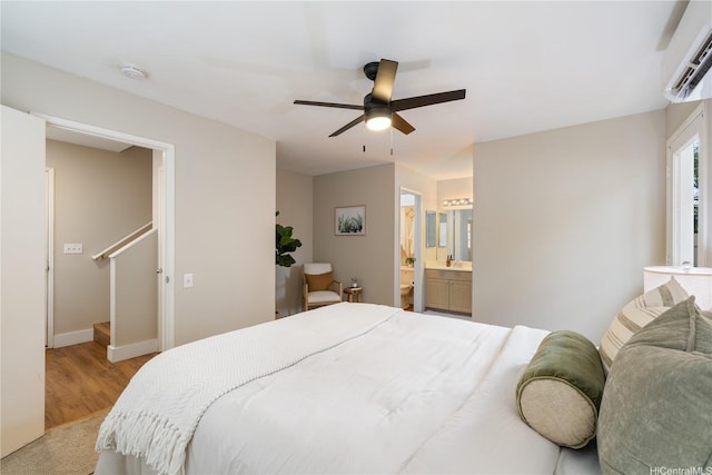91-1860 Luahoana St Unit 114, Ewa Beach, HI 96706 - bedroom featuring an AC wall unit, light wood-style flooring, baseboards, a ceiling fan, and ensuite bath