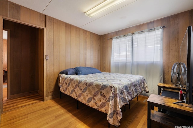 bedroom with wooden walls and light wood-style flooring