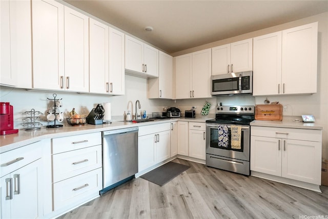 91-3633 Kauluakoko St Unit 5204, Ewa Beach, HI 96706 - kitchen featuring light countertops, white cabinets, a sink, light wood-style flooring, and appliances with stainless steel finishes