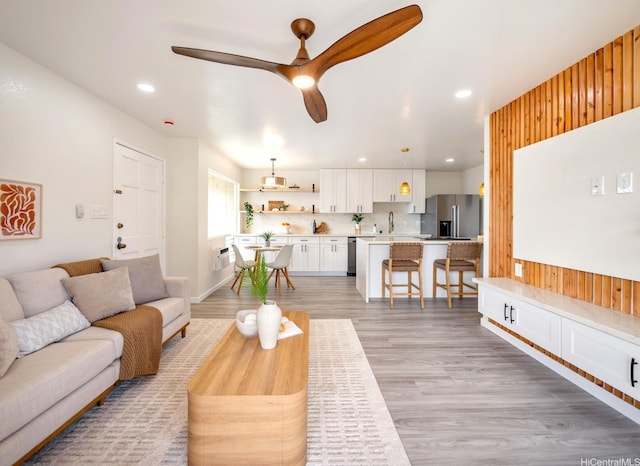 living area featuring light wood-style flooring, a ceiling fan, and recessed lighting