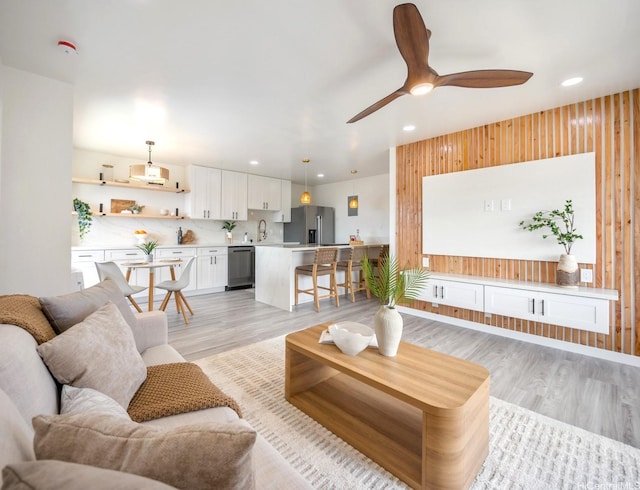 living area with light wood-style flooring, a ceiling fan, and recessed lighting