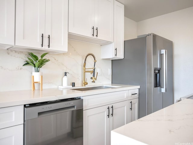 kitchen featuring a sink, tasteful backsplash, white cabinets, and appliances with stainless steel finishes