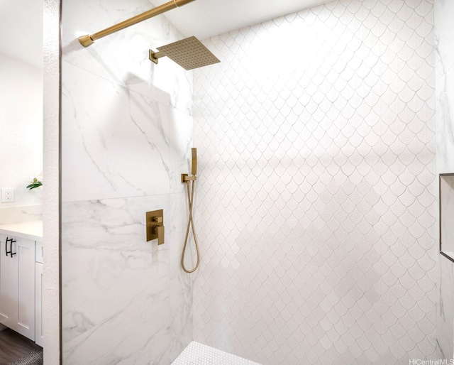 full bathroom with a tile shower and vanity