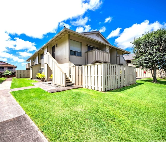 back of property with stairway, fence, and a lawn