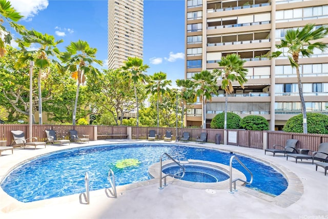 community pool featuring fence, a patio, and a hot tub