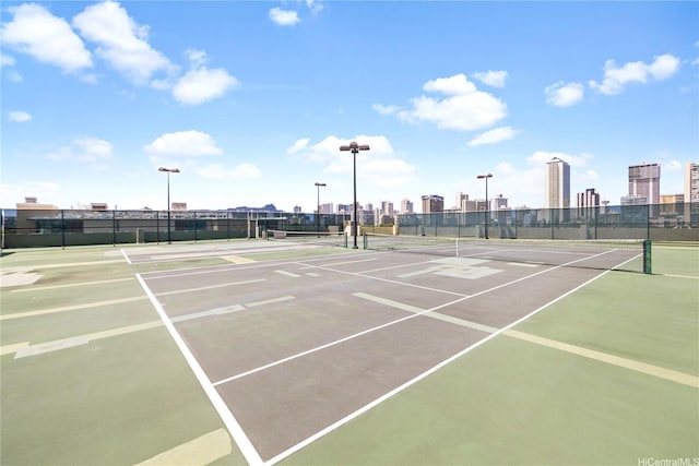 view of tennis court with a view of city, community basketball court, and fence