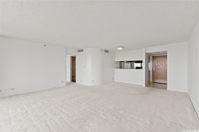 unfurnished living room with visible vents, carpet flooring, and a textured ceiling