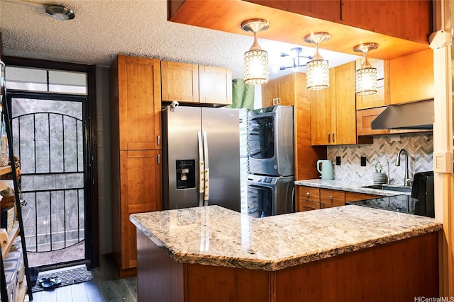 95-273 Waikalani Dr Unit D501, Mililani, HI 96789 - kitchen featuring oven, stainless steel refrigerator with ice dispenser, stacked washer and clothes dryer, under cabinet range hood, and brown cabinetry
