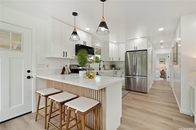 45-127 Waikapoki Rd Unit D, Kaneohe, HI 96744 - kitchen featuring stainless steel appliances, a peninsula, white cabinetry, a breakfast bar area, and light wood-style flooring