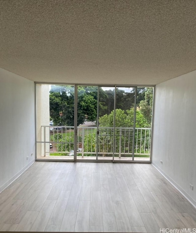 98-410 Koauka Loop Unit 4B, Aiea, HI 96701 - empty room featuring a textured ceiling, wood finished floors, and a wall of windows