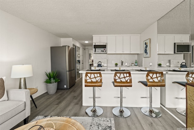 2211 Ala Wai Blvd Unit 2015, Honolulu, HI 96815 - kitchen with a textured ceiling, dark wood-style flooring, appliances with stainless steel finishes, and a breakfast bar