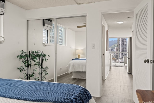 2211 Ala Wai Blvd Unit 2015, Honolulu, HI 96815 - bedroom featuring a textured ceiling, baseboards, an AC wall unit, and wood finished floors