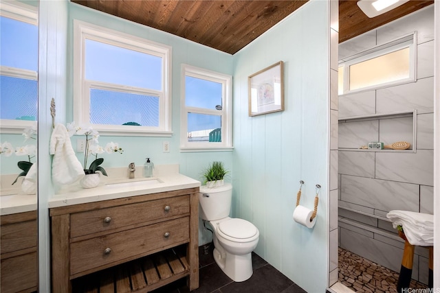 bathroom featuring vanity, toilet, tiled shower, wood ceiling, and tile patterned floors