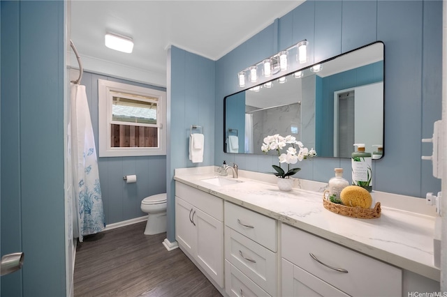 full bath featuring wood finished floors, baseboards, vanity, toilet, and ornamental molding