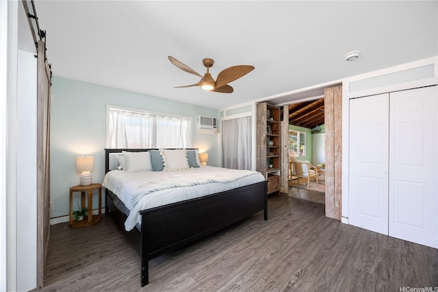 bedroom featuring a barn door, ceiling fan, a wall unit AC, and wood finished floors
