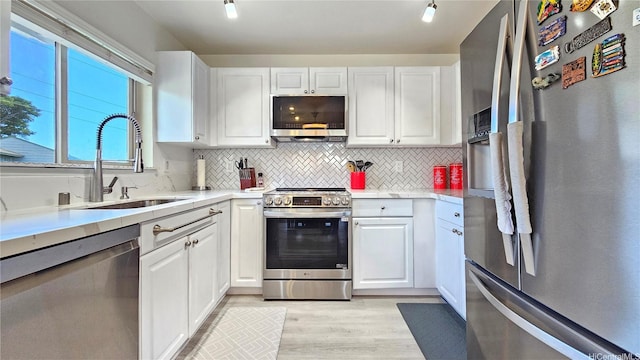 92-1145 Panana St Unit 1608, Kapolei, HI 96707 - kitchen with appliances with stainless steel finishes, a sink, light countertops, light wood-style flooring, and white cabinetry