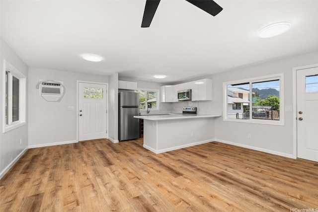 kitchen featuring a ceiling fan, appliances with stainless steel finishes, light countertops, a peninsula, and white cabinetry