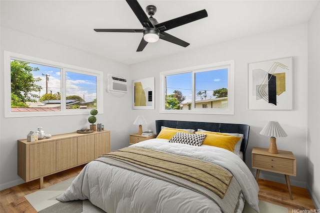 bedroom with radiator, multiple windows, a wall mounted AC, and wood finished floors