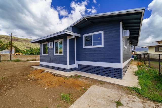 view of side of property featuring fence and a wall unit AC