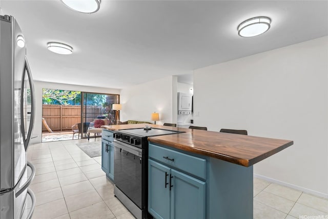 68-090 Au St Unit E102, Waialua, HI 96791 - kitchen with blue cabinets, range with electric cooktop, light tile patterned floors, freestanding refrigerator, and butcher block counters