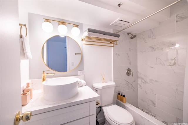 bathroom featuring toilet, tiled shower, vanity, and visible vents