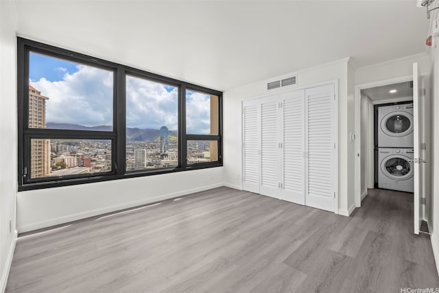 1600 Ala Moana Blvd Unit 2700, Honolulu, HI 96815 - unfurnished bedroom featuring stacked washer / drying machine, a closet, wood finished floors, a mountain view, and baseboards