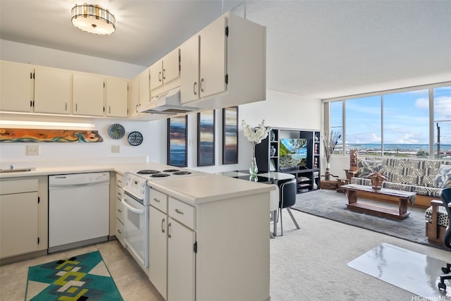 kitchen featuring light countertops, a peninsula, under cabinet range hood, and white appliances