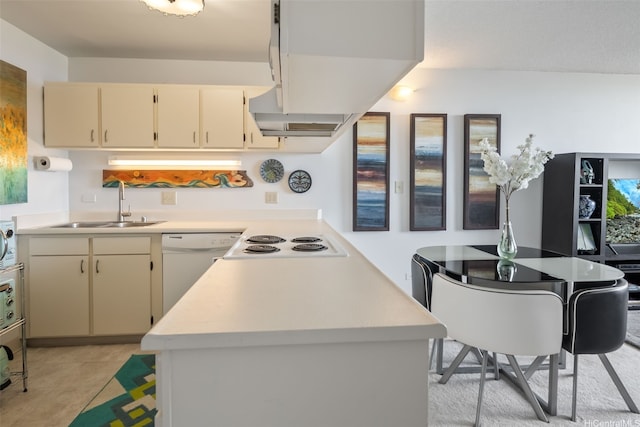 kitchen featuring white appliances, a peninsula, a sink, and light countertops