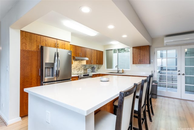 kitchen featuring brown cabinets, stainless steel appliances, a wall mounted air conditioner, and a sink